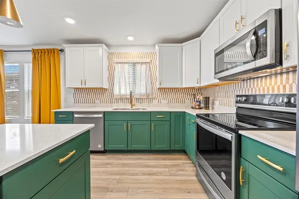 a kitchen with stainless steel appliances granite countertop a sink a stove a microwave cabinets and a window