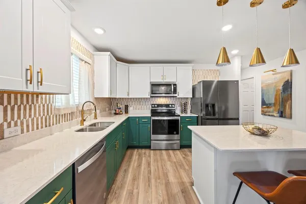 a kitchen with stainless steel appliances a sink dishwasher a stove a refrigerator with a dining table and chairs