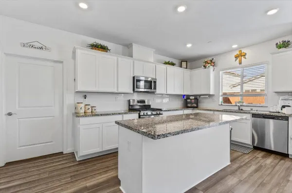 a kitchen with granite countertop a sink stainless steel appliances and cabinets