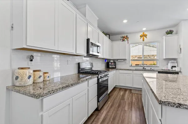 a kitchen with granite countertop white cabinets white appliances and a sink