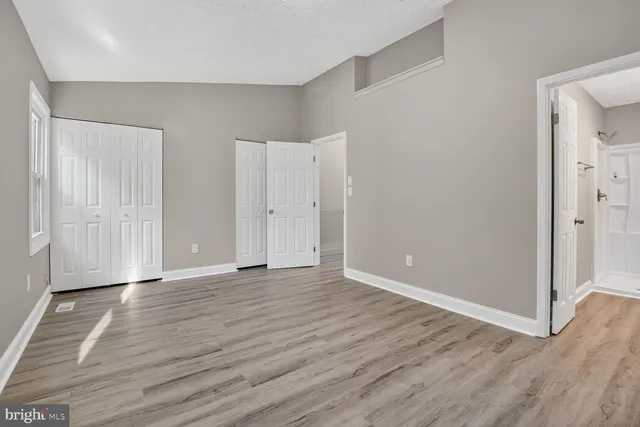 a view of empty room with wooden floor and fireplace