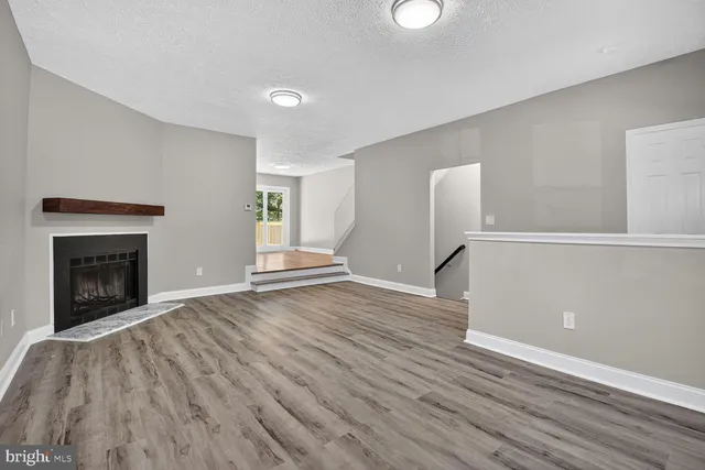 a view of empty room with wooden floor and fireplace