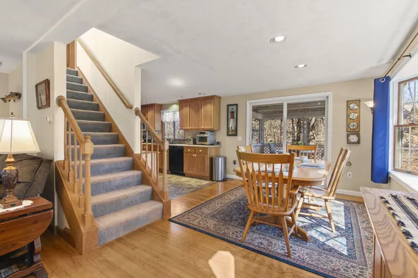a view of a dining room with furniture one side kitchen view and wooden floor