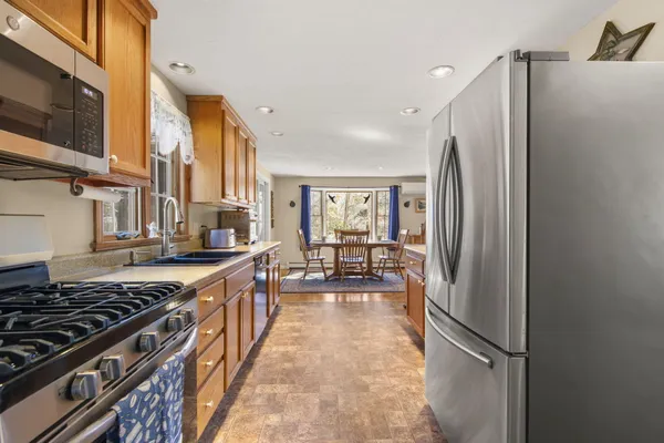a kitchen with stainless steel appliances granite countertop a refrigerator a stove and a sink with wooden floor