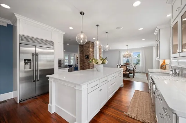 a large kitchen with stainless steel appliances kitchen island a large counter top a sink a stove and a refrigerator