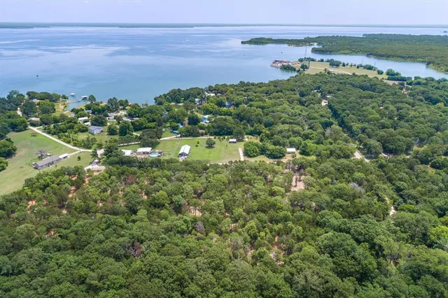 an aerial view of a houses with a yard and lake view