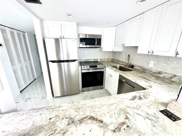 a kitchen with granite countertop a refrigerator sink and microwave