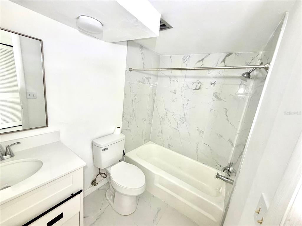 4550 Cove Circle, Unit 905 St. Petersburg, FL 33708 - Photo 8 of 17 a bathroom with a granite countertop sink toilet and shower