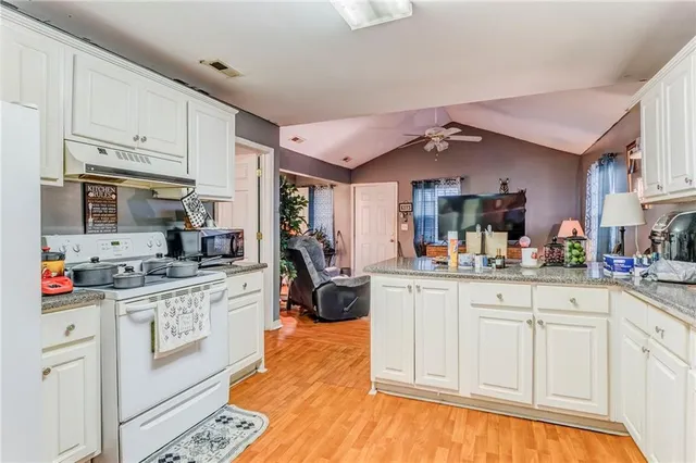 a kitchen with granite countertop a sink cabinets stainless steel appliances and a window