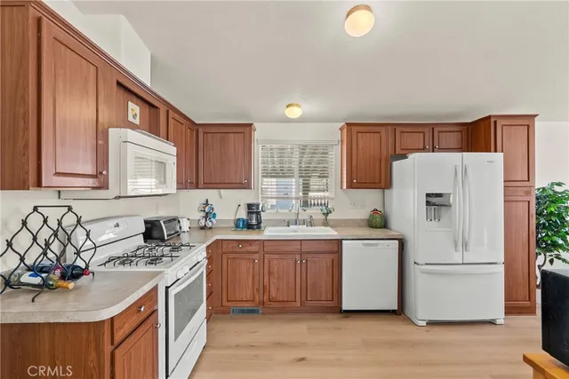 a kitchen with granite countertop a refrigerator a sink dishwasher stove and oven with wooden floor