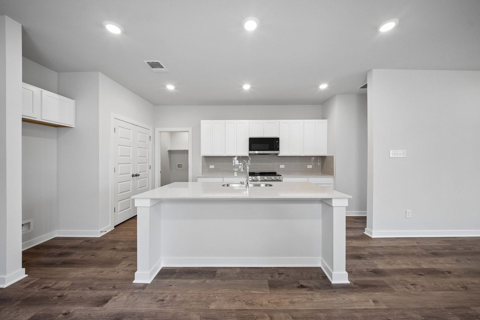 145 Hornet Street Elgin, TX 78621 - Photo 14 of 18 A contemporary kitchen features a spacious island and dark wood flooring, offering both style and functionality.