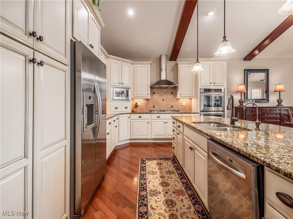 5349 Slater Ridge Westerville, OH 43082 - Photo 10 of 50 Kitchen with appliances with stainless steel finishes, beam ceiling, hanging light fixtures, dark wood-style floors, and tasteful backsplash
