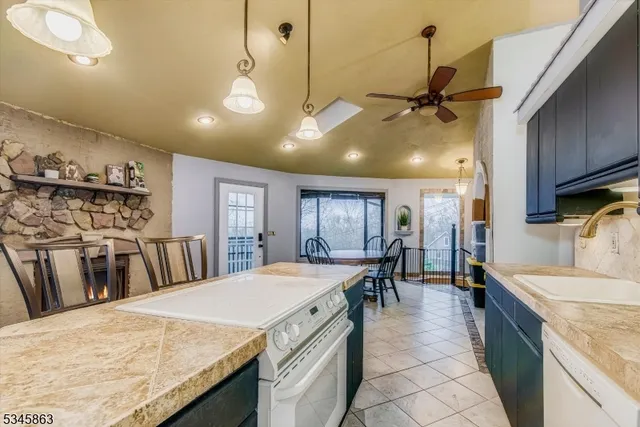 a kitchen with granite countertop a stove a sink a dining table and chairs with wooden floor