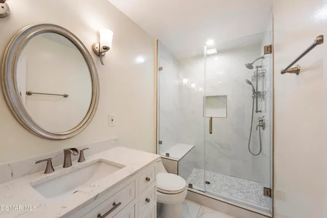 a bathroom with a granite countertop sink a toilet and a mirror