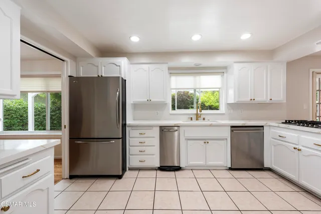 a kitchen with white cabinets white appliances and sink