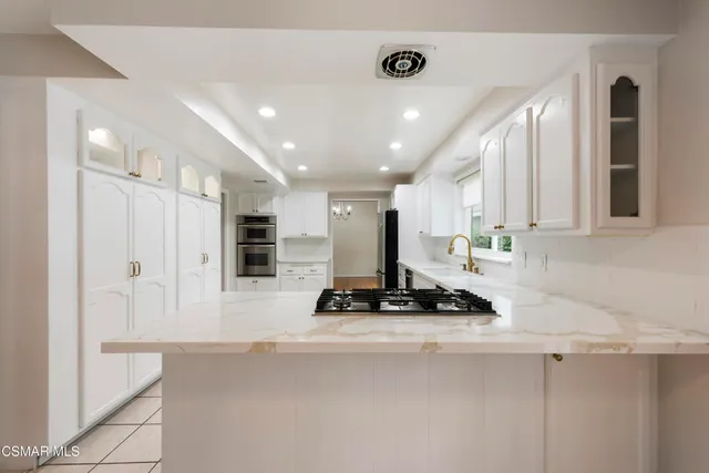 a kitchen with stainless steel appliances a refrigerator a sink and white cabinets