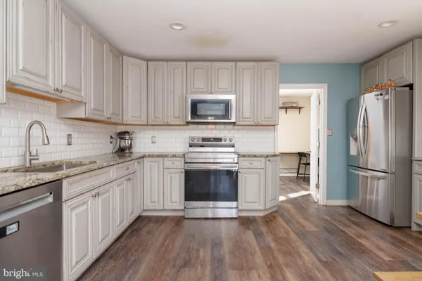a kitchen with granite countertop a refrigerator stove and sink