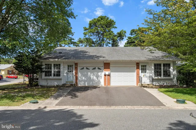 a front view of a house with a garden and trees