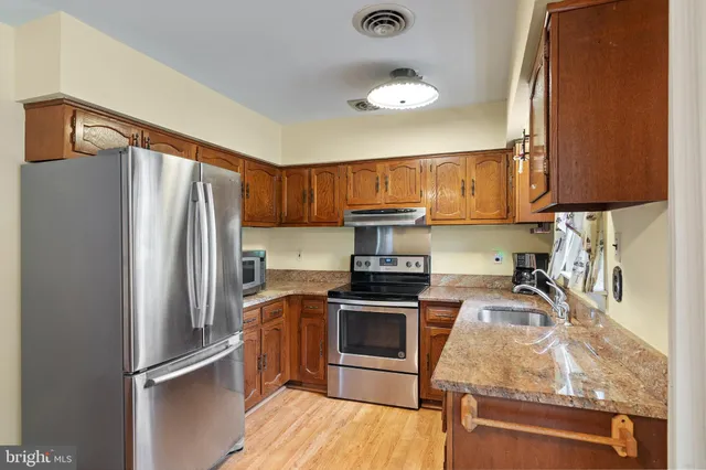 a kitchen with stainless steel appliances granite countertop a refrigerator stove and sink