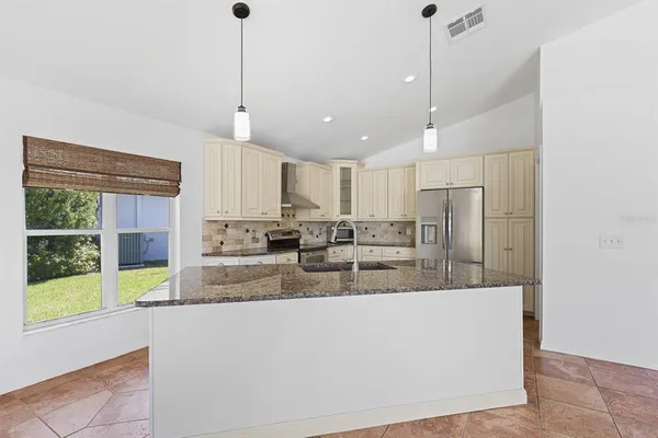 a kitchen with stainless steel appliances granite countertop a refrigerator and white cabinets