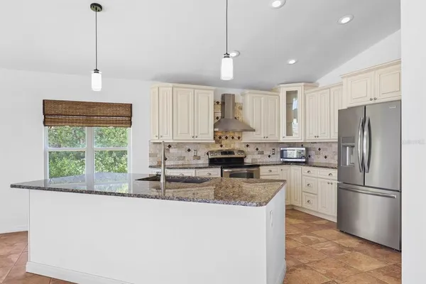 a view of kitchen with stainless steel appliances kitchen island a refrigerator sink and white cabinets
