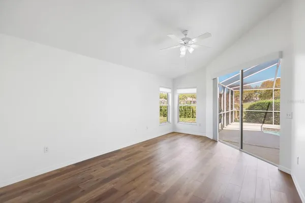 an empty room with windows and ceiling fan