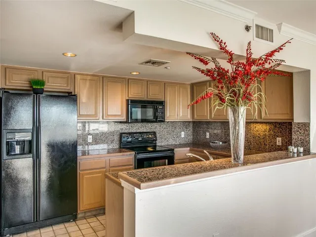 a kitchen with stainless steel appliances granite countertop a refrigerator a sink dishwasher and a microwave oven