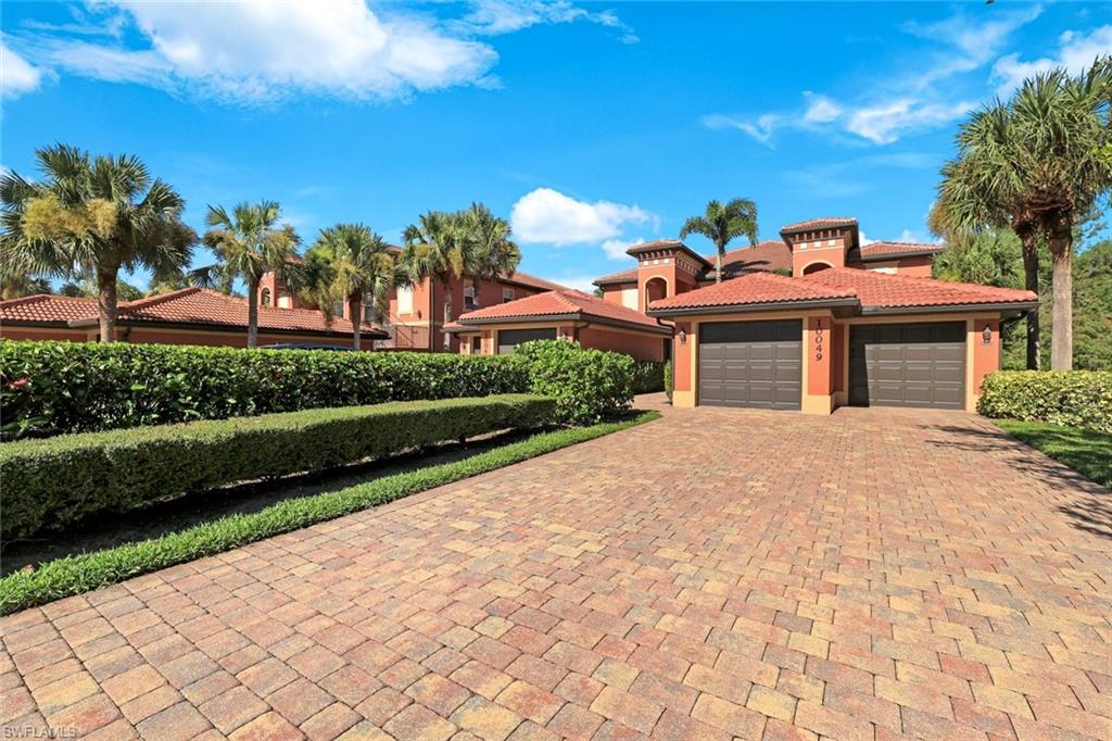 10049 Heather Lane, Unit 101 Naples, FL 34119 - Photo 1 of 28 View of front of home featuring decorative driveway, stucco siding, a tiled roof, and an attached garage