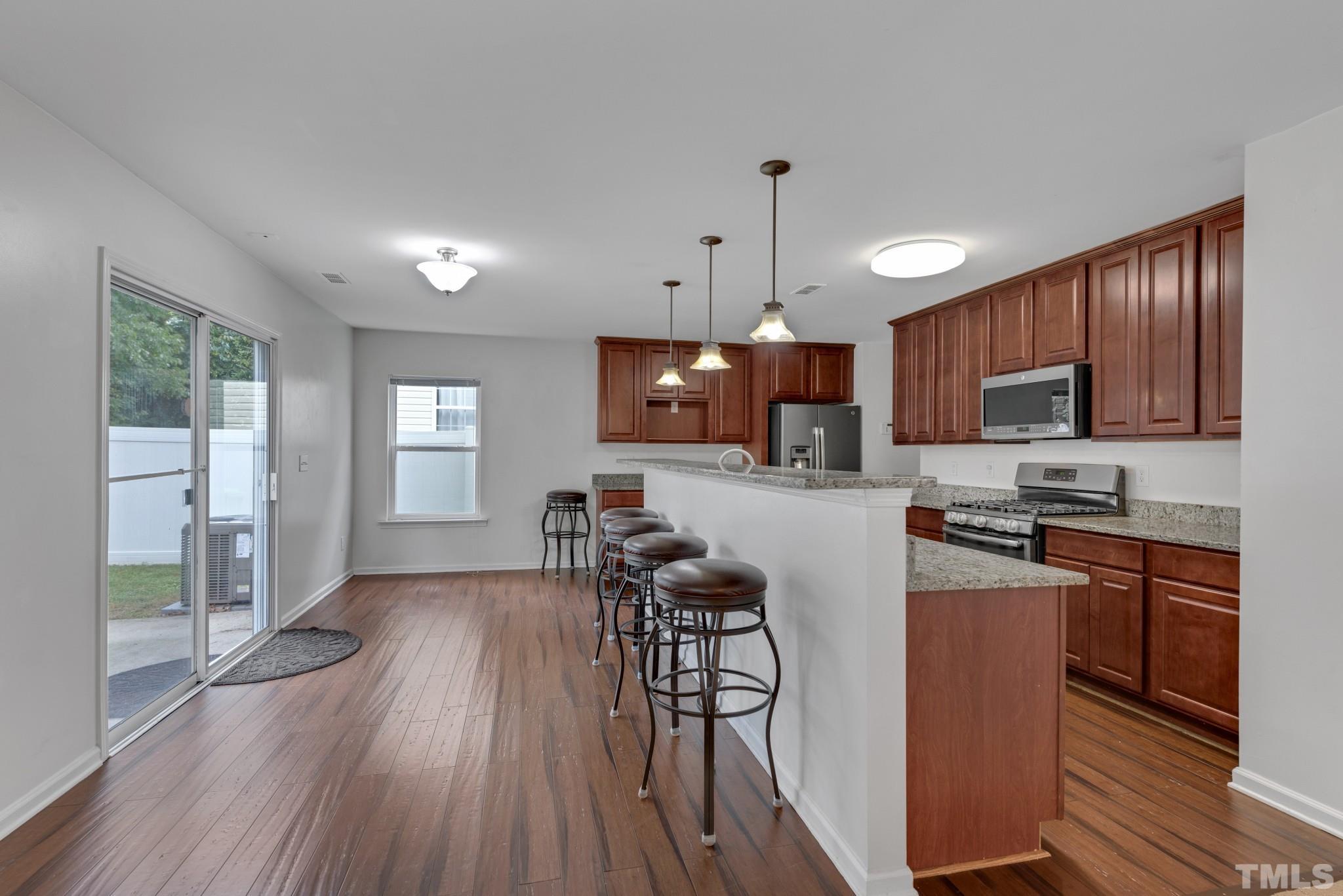 2824 Roundleaf Court Raleigh, NC 27604 - Photo 4 of 35 a kitchen with stainless steel appliances wooden floors wooden cabinets dining table and chair