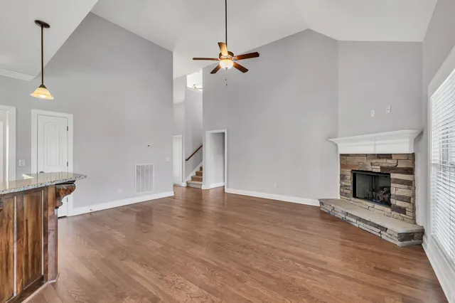 a view of an empty room with wooden floor fireplace and a window