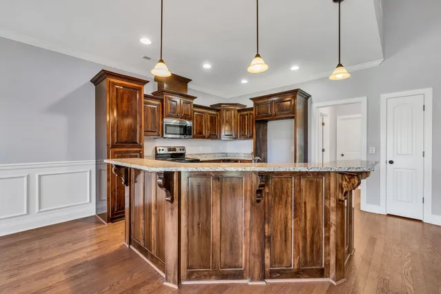 a kitchen with stainless steel appliances granite countertop a refrigerator a sink dishwasher a stove and white cabinets with wooden floor