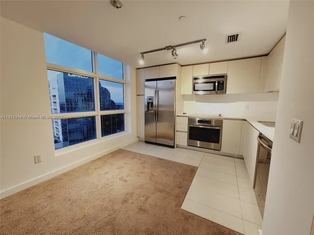 a view of a kitchen with a sink and a refrigerator