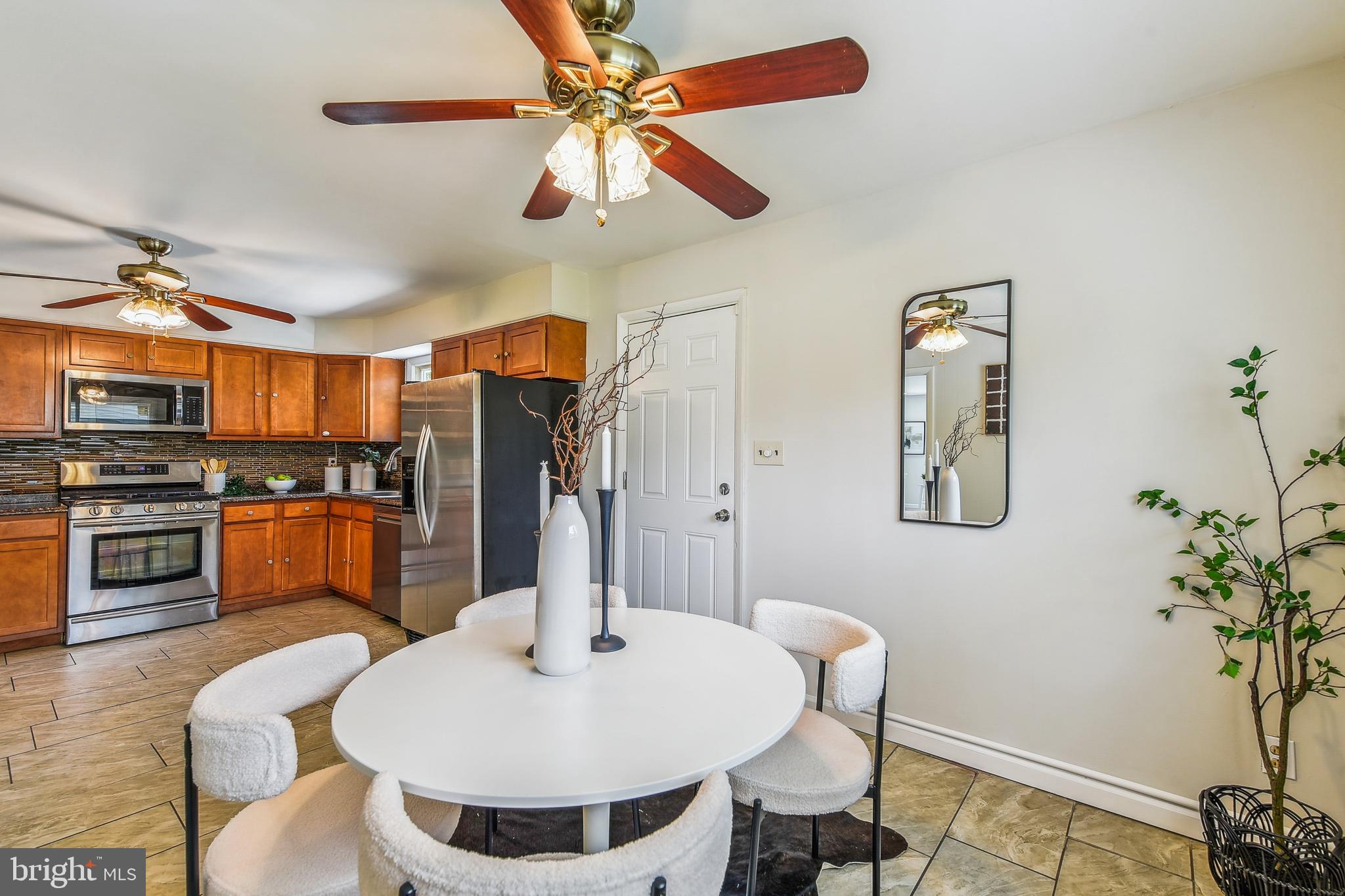 8148 Scotts Level Road Pikesville, MD 21208 - Photo 11 of 36 a kitchen with stainless steel appliances kitchen island granite countertop a refrigerator a stove a sink a dining table and chairs with wooden floor
