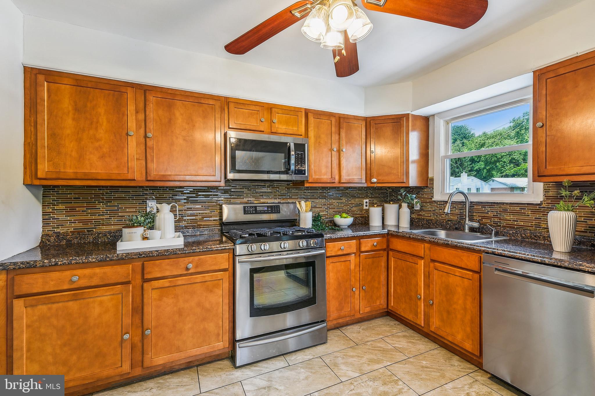 8148 Scotts Level Road Pikesville, MD 21208 - Photo 13 of 36 a kitchen with stainless steel appliances granite countertop a stove sink microwave and refrigerator