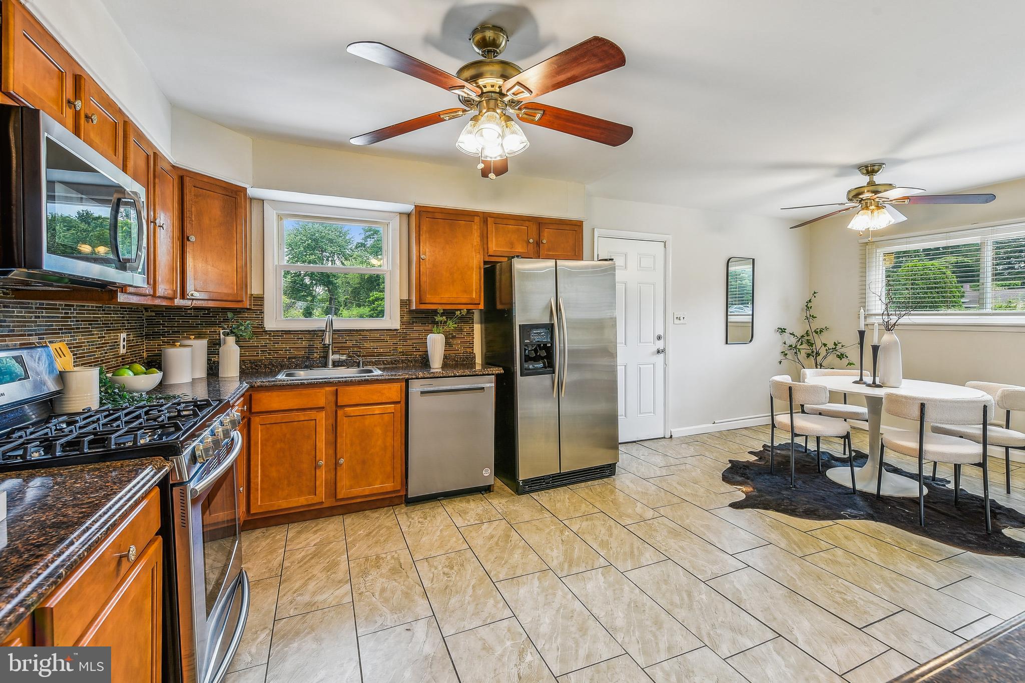 8148 Scotts Level Road Pikesville, MD 21208 - Photo 14 of 36 a kitchen with stainless steel appliances granite countertop a stove refrigerator a sink dishwasher with a dining table and chairs
