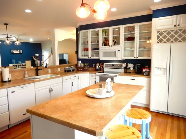 a kitchen with stainless steel appliances kitchen island granite countertop a refrigerator and cabinets