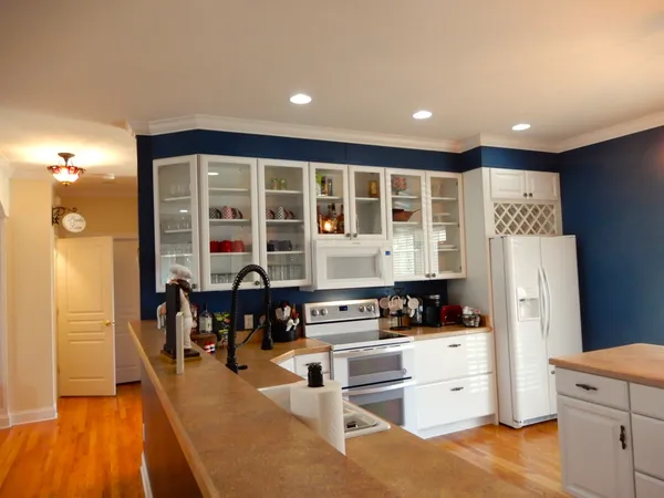 a kitchen with stainless steel appliances kitchen island granite countertop a refrigerator and a sink