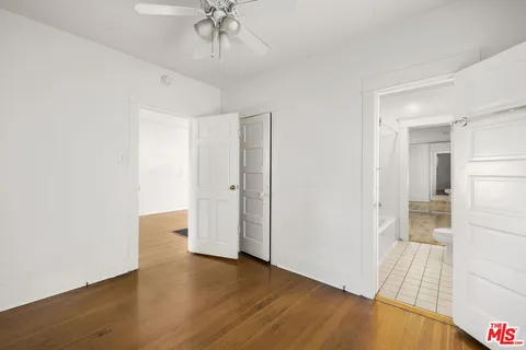 an empty room with wooden floor and ceiling fan