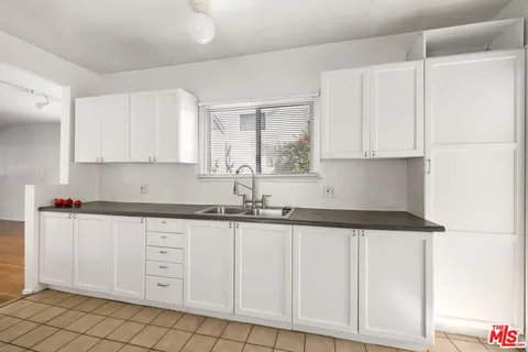 a kitchen with granite countertop white cabinets and sink