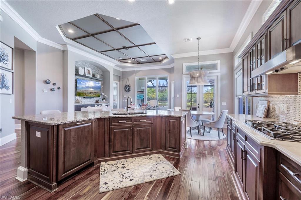 3086 Aviamar Circle Naples, FL 34114 - Photo 12 of 50 a kitchen with stainless steel appliances granite countertop a stove a sink dishwasher a dining table and chairs with wooden floor