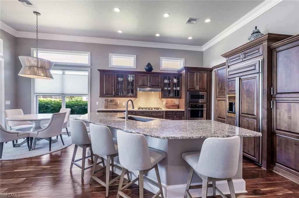 3086 Aviamar Circle Naples, FL 34114 - Photo 10 of 50 a kitchen with granite countertop a table chairs stainless steel appliances and wooden floor