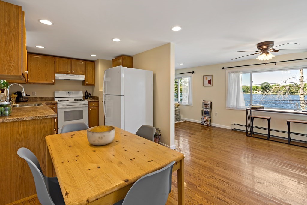55 Alpine Road Weymouth, MA 02189 - Photo 16 of 31 a kitchen with a refrigerator a stove top oven a sink and dining table with wooden floor