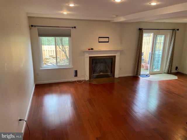 an empty room with wooden floor fireplace and windows