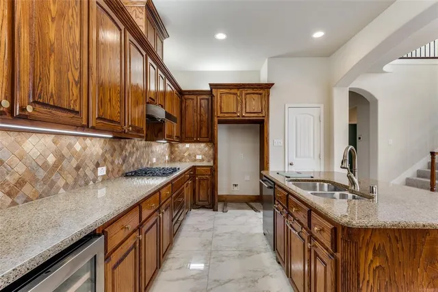 a kitchen with stainless steel appliances granite countertop a sink a stove and a wooden floors