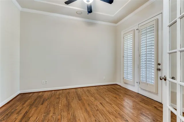 an empty room with wooden floor cabinet and windows