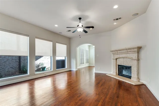 an empty room with wooden floor fireplace and windows