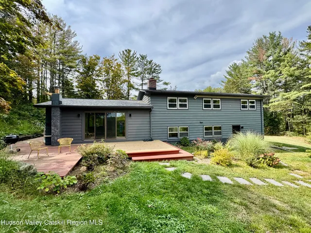 a front view of house with yard and trees in the background
