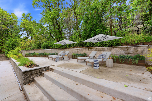 1389 Millbrook Way Bountiful, UT 84010 - Photo 65 of 74 Multi-level concrete patio with integrated planter boxes and retaining walls, surrounded by mature trees