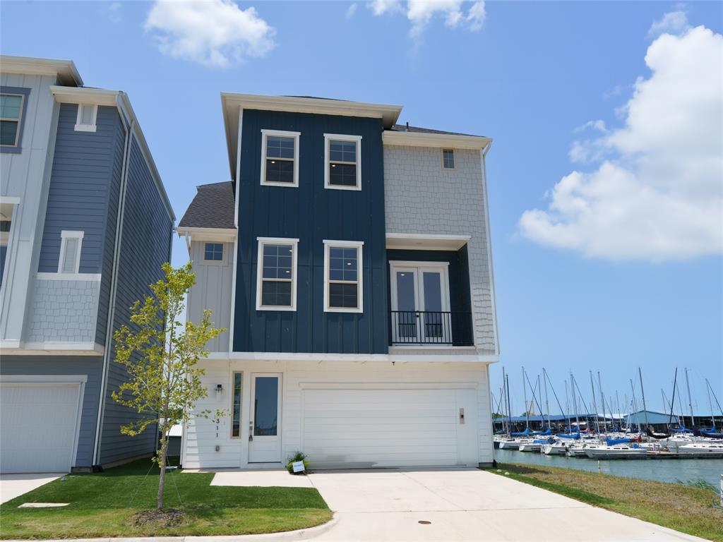 View of front of home featuring a balcony, board and batten siding, view of marina, driveway, and a garage