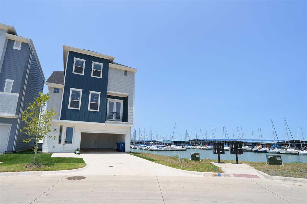 9311 Easy Street Rowlett, TX 75088 - Photo 21 of 22 View of front of property featuring view of marina, board and batten siding, a balcony, a water view, and driveway